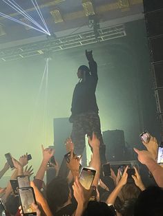 a man standing on top of a stage surrounded by people holding up their cell phones