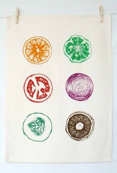 four different fruits and vegetables are drawn on a white wall hanging from a clothes line