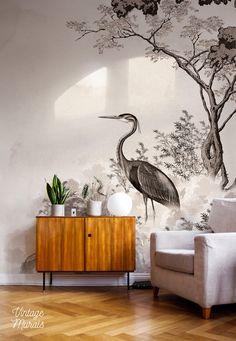 a living room with a couch, chair and painting on the wall behind it that has a bird standing next to a tree