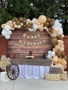 an outdoor birthday party with balloons, hay bales and a sign that says happy birthday