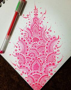 a pen is sitting on top of a notebook with an intricately designed design in red and white