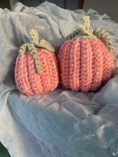 two crocheted pumpkins sitting on top of a white cloth covered tablecloth