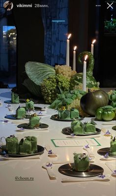 a table topped with plates and candles filled with green food covered in frosted icing