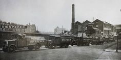 an old black and white photo of trucks parked on the side of a road in front of buildings