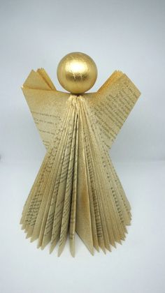 an origami sculpture made out of book pages with a golden ball on top