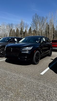 several cars parked in a parking lot with trees in the backgroung and snow on the ground