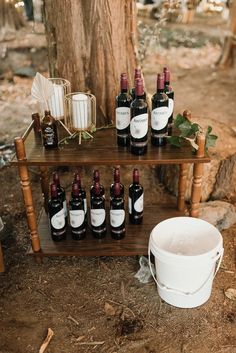 a wooden table topped with bottles of wine next to a bucket filled with liquid and candles