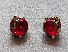 "Vintage 1940s era rhinestone earrings. Earrings are clip back style and feature red rhinestone chatons prong set, open back and unfoiled. Decorative swirl with black enamel over the stones. Earrings will arrive gift boxed. HALLMARKS Unmarked. SIZE 5/8\" across. MATERIALS Glass, Enamel and gilded metal. CONDITION In very good condition with original stones. Please use all pictures as part of item's description." Stones Earrings, Enamel Earrings, Red Rhinestone, Rhinestone Earrings, Red Glass, Black Enamel, Jewelry Earrings Studs, Prong Setting, Hallmark