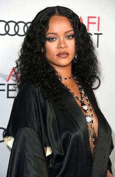 an image of a woman with long hair wearing a black dress and statement necklaces