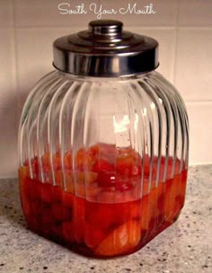 a jar filled with fruit sitting on top of a counter