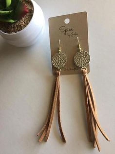 earrings with tassels are sitting next to a potted plant