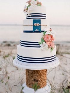 a white and blue wedding cake sitting on top of a rope