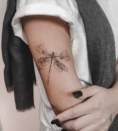 a woman's arm with a dragonfly tattoo on it