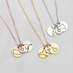 three necklaces with different designs on them, one is gold and the other is silver