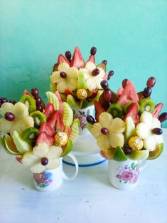 three cups filled with assorted fruit on top of a white table next to each other