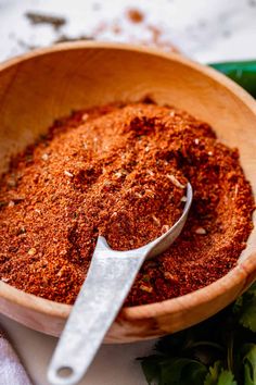 a wooden bowl filled with spices next to a spoon