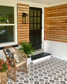 two wicker chairs sitting on a porch next to a potted plant and door