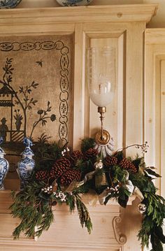 a fireplace mantel decorated for christmas with evergreen and pine cones