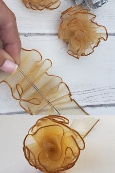 a person is cutting up some sort of flower decoration on a white wooden table with scissors