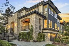 a large home with stone and brick exterior, stairs leading up to the front door