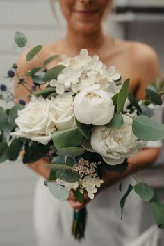 a woman holding a bouquet of white flowers