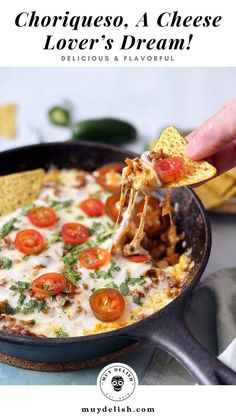 someone holding a tortilla chip with cheese, tomatoes and other toppings in a cast iron skillet