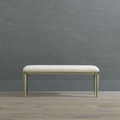 a bench sitting on top of a hard wood floor next to a gray painted wall