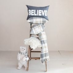 a teddy bear sitting next to a chair with a pillow on it