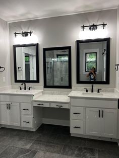 a bathroom with two sinks and three mirrors