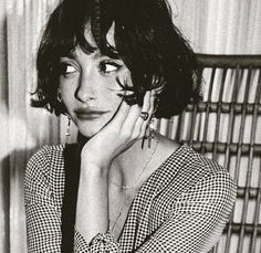 a black and white photo of a woman with her hand on her chin, looking at the camera