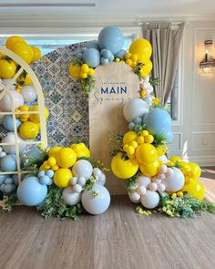 balloons and greenery are arranged on the floor in front of a sign that reads main st