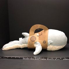 a white stuffed animal laying on top of a black table next to a ruler and measuring tape