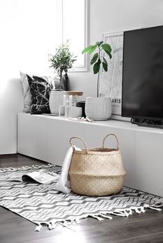 a flat screen tv sitting on top of a white shelf next to a potted plant