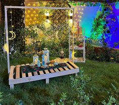 a picnic table set up in the middle of a garden at night with lights on it