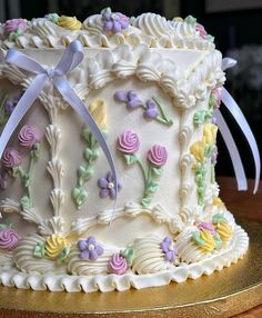 a decorated cake with flowers and ribbons on a table