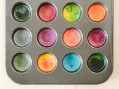 a muffin tin filled with lots of different colored cupcakes