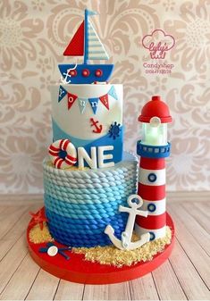 a three tiered cake is decorated with an anchor, lighthouse and life preserver