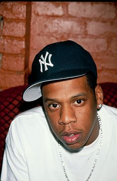 a close up of a person wearing a baseball cap and pearls on a chain necklace