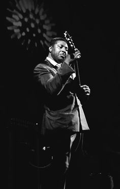 a black and white photo of a man playing the guitar