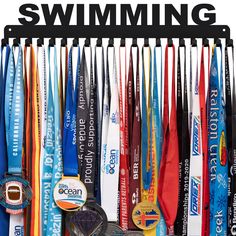 an assortment of swimming medals hanging on a rack with the words swimming written above them