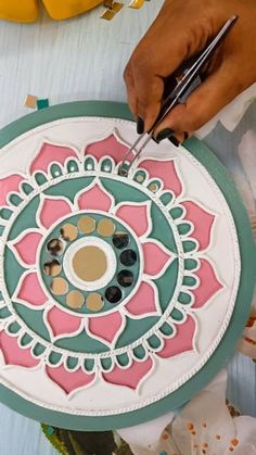 a person is using scissors to paint a flower design on a paper plate with flowers in the background