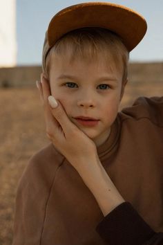 a young boy in a brown shirt and hat