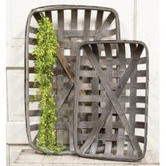 two metal baskets with plants in them on top of a wooden shelf next to a white wall