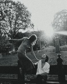 a man kneeling down on top of a bench next to a woman who is touching her hand