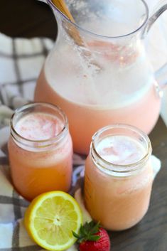 three jars filled with liquid next to lemons and strawberries