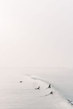 two people riding skis on top of a large body of water near the shore