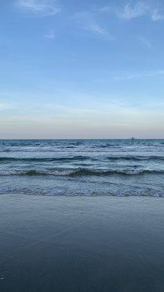 an ocean view with waves coming in to shore and the sky above it is blue