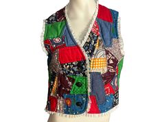 a white mannequin wearing a multicolored vest with patches and buttons on it