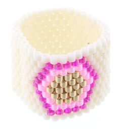 a pink and white beaded bracelet with gold squares on the front, sitting against a white background