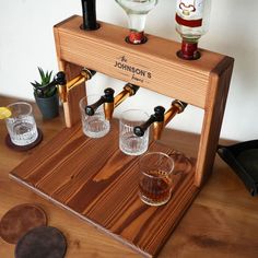 three shot glasses on a wooden stand with liquor bottles